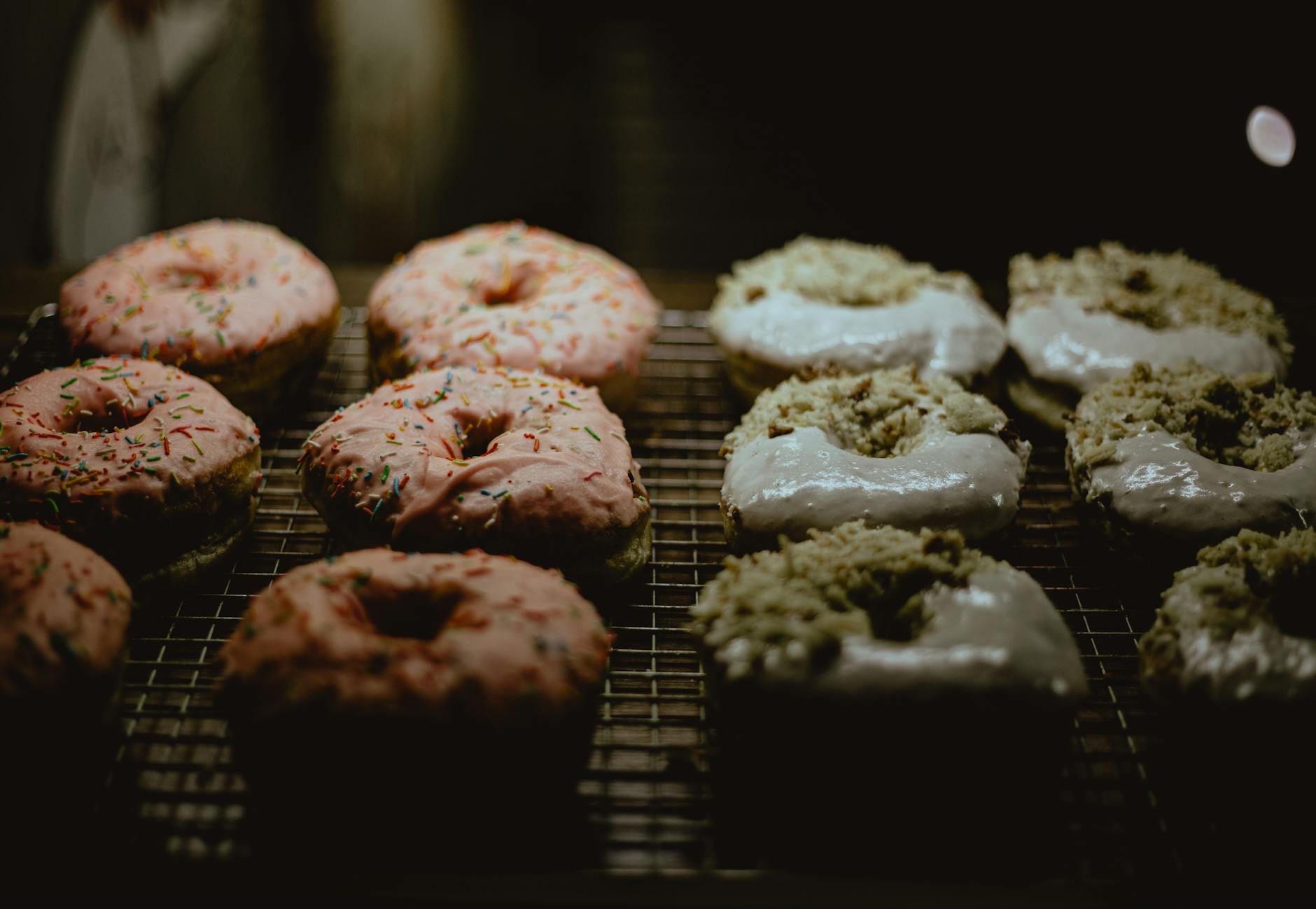 pink and white glazed donuts on metal grill